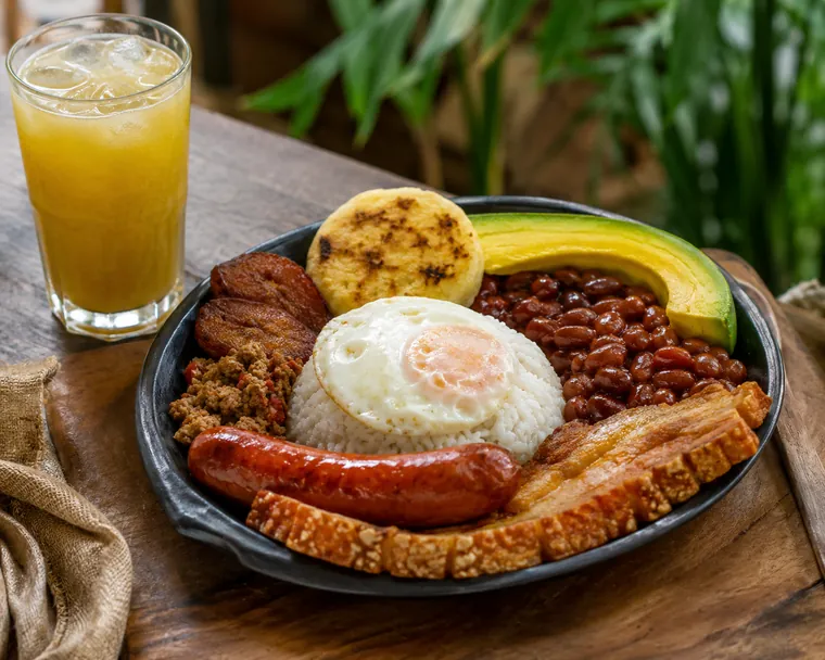 Foto del almuerzo del día: bandeja paisa con frijoles, arroz, huevo, chicharrón, chorizo, arepa, aguacate y jugo natural.